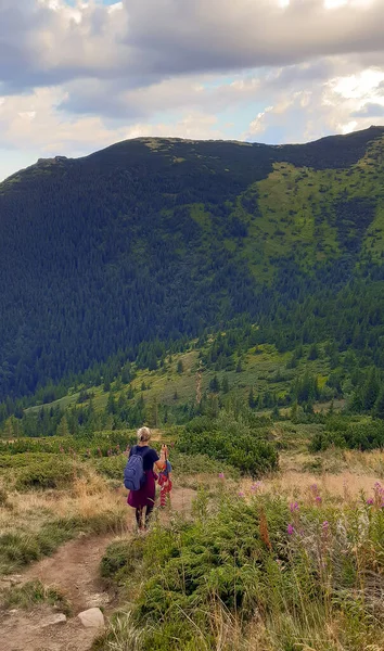Kobieta i dziecko schodzą po zboczu góry wzdłuż ścieżki. Góra w tle — Zdjęcie stockowe