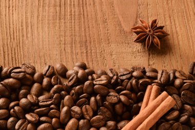 Fotoğrafın dibine kahve çekirdekleri serpiştirilmiş. Ayrıca anason ve tarçın. Boş ahşap arkaplanın üst fotoğrafı