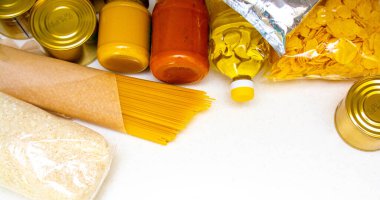 Karton bir kutuda çeşitli konserve yiyecekler, makarna ve mısır gevrekleri. Yiyecek bağışları ya da yiyecek teslimatı kavramı.