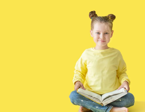 Sarı arka planda oturan, kitap okuyan, gelişim ve okul kavramını anlatan sarı ceketli komik kız çocuğu okula geri döndü.