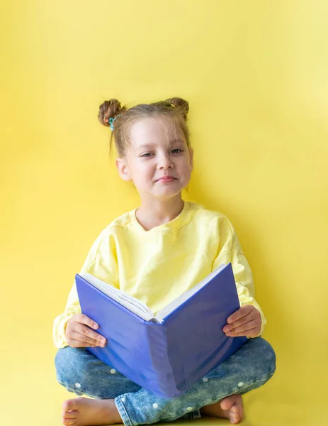 Sarı arka planda oturan, kitap okuyan, gelişim ve okul kavramını anlatan sarı ceketli komik kız çocuğu okula geri döndü.
