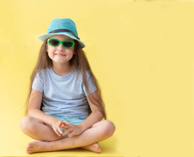 Seyahat konsepti. Sarı arka planda mavi şapkalı bir kızın portresi..