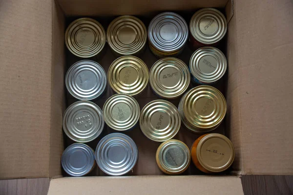 Various canned food, pasta and cereals in a cardboard box. Food donations or food delivery concept.