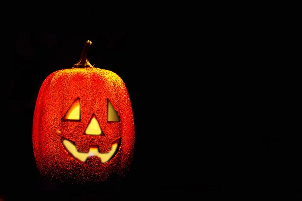 Halloween pumpkin smile and scary eyes for a party at night. Close-up view of a scary Halloween pumpkin with eyes glowing inside on a black background. Selective focus. Space for text.