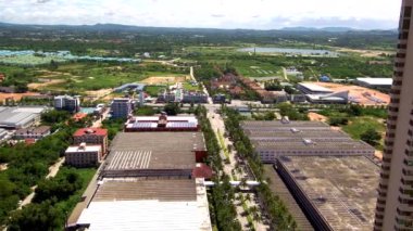 Tayland sahilindeki prestijli yüksek otelin 4K görüntüsü. Otelin arkasında sanayi binaları, küçük evler ve bir göl var. Ufukta yüksek dağlar görülebilir. 