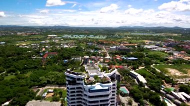 Tayland kıyısındaki yüksek prestijli bir otelin 4K çatı manzarası. Güneş ışığı çatıdan balkona yansıyor. Çatıda ağaçlar, uydu antenleri, pergolalar var. Ufukta adaları ve yüksek dağları görebilirsiniz.. 
