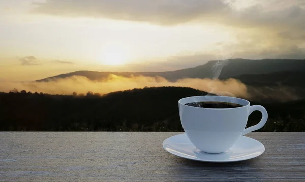 热的黑咖啡在白咖啡杯里有一点烟 白色的杯子放在一个粗糙的 闪闪发光的木地板上 早晨阳光普照 多雾的山景和阳光 3D渲染 — 图库照片