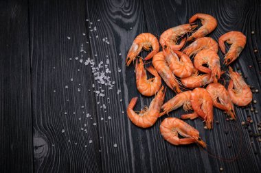 Koyu arkaplanda tuzlu ve biberli haşlanmış karides.