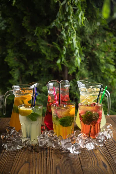 Homemade strawberry ice tea in the garden. Strawberries, mint and lemon balm leaves, ice and green tea.