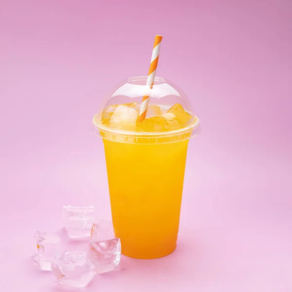 Yaz İçeceği Taze Limonata. Pembe arka planda, plastik bardakta turuncu.