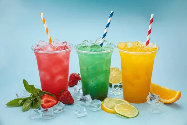 Kolorowe Lemoniady Plastikowych Filiżanek Lodem Owocami Jagodami Niebieskim Tle — Zdjęcie stockowe