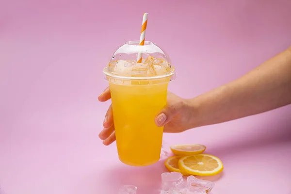 Yaz İçeceği Taze Limonata. Pembe arka planda, plastik bardakta turuncu.