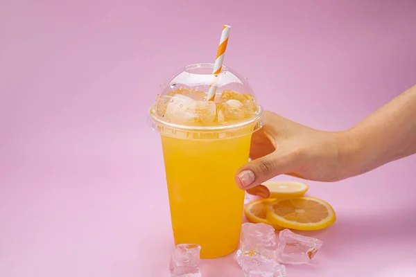 Yaz İçeceği Taze Limonata. Pembe arka planda, plastik bardakta turuncu.