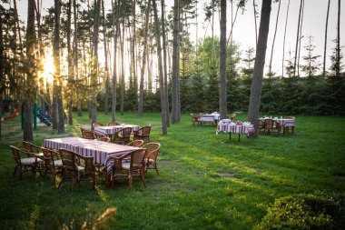 Masalar çam ağaçlarının arasındaki bir açıklıkta servis edilir. Yaz güneşi batıyor
