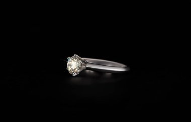 Siyah arka planda izole edilmiş elmas değerli taşlı altın bir yüzük.