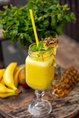 Ahşap zemin üzerinde ananas, mango, muz ve nane ile serin smoothie