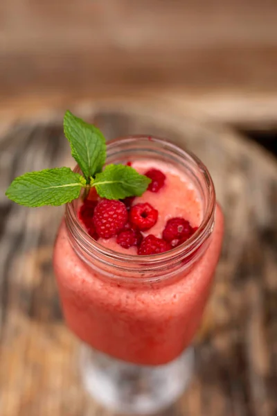 Cool smoothie with raspberries on a wooden background
