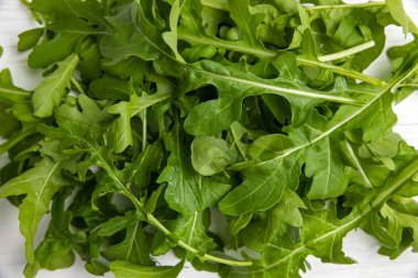 Beyaz ahşap bir masada taze çiftlik roka 'sı.