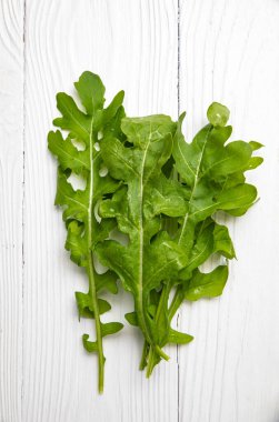 Beyaz ahşap bir masada taze çiftlik roka 'sı.