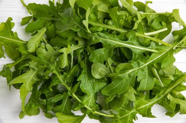 Beyaz ahşap bir masada taze çiftlik roka 'sı.