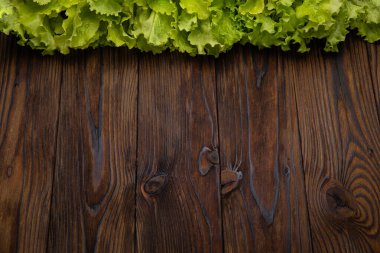 Kahverengi ahşap arka planda taze marul yaprakları.