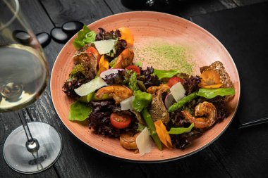 Deniz mahsullü salata, kuşkonmaz, domates, koyu arkaplanda sos.