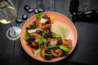 Deniz mahsullü salata, kuşkonmaz, domates, koyu arkaplanda sos.