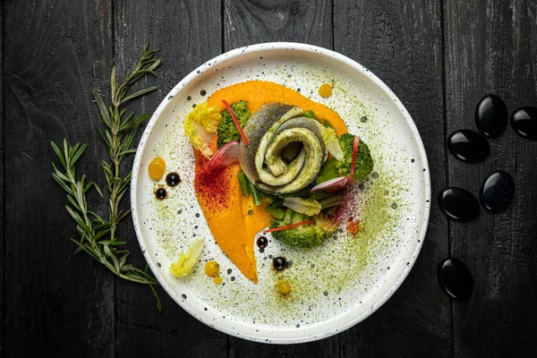 Özel bir restoranda pişirilmiş deniz balığı soslu ve sebzeli püre soslu beyaz bir patikada.