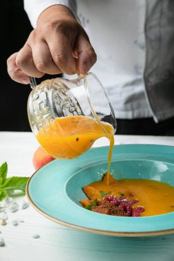 Soğuk mango-tutkulu meyve çorbası. Beyaz ahşap bir masada