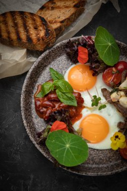 Kahvaltıda domatesli yumurta, fasulye, et, peynir ve sos.