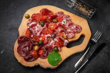 Tütsülenmiş et, sosis, parma, ahşap bir tahtada jamon ve koyu beton bir masa..