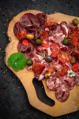 Tütsülenmiş et, sosis, parma, ahşap bir tahtada jamon ve koyu beton bir masa..