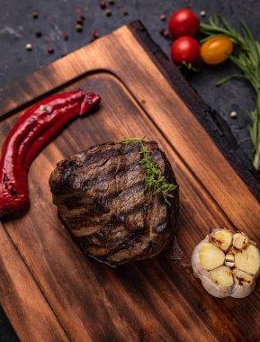 Amerikan sulu bifteği, baharatlar, domates ve ızgara sebzelerle birlikte. Siyah bir masada. 