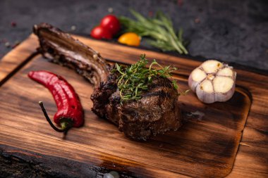 Amerikan sulu bifteği, baharatlar, domates ve ızgara sebzelerle birlikte. Siyah bir masada. 