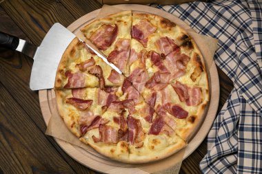 Pizza, stokta. Kahverengi ahşap bir masada.