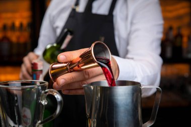 Siyah önlüklü, gülümseyen genç bir barmen sıcak şarap hazırlar.