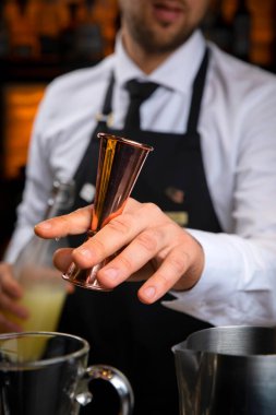 Siyah önlüklü, gülümseyen genç bir barmen sıcak şarap hazırlar.