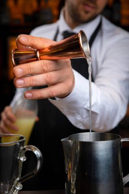 Siyah önlüklü, gülümseyen genç bir barmen sıcak şarap hazırlar.