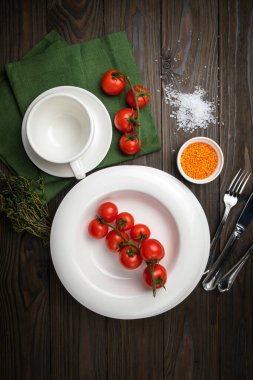 Tabaklar ahşap bir masanın üzerine serilmiştir. Kiraz, çimen, kap kacak, deniz tuzu.