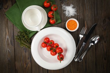 Tabaklar ahşap bir masanın üzerine serilmiştir. Kiraz, çimen, kap kacak, deniz tuzu.