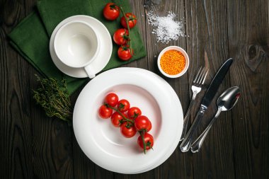 Tabaklar ahşap bir masanın üzerine serilmiştir. Kiraz, çimen, kap kacak, deniz tuzu.