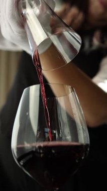 Şeffaf bir sürahide kırmızı şarap. Yavaş çekim videosu, yakın çekim. Barmen şarap hazırlar..