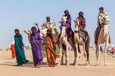Tuareg people in traditional clothes sitting on camels in Sahara desert
