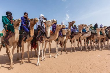 Tuareg people in traditional clothes sitting on camels in Sahara desert