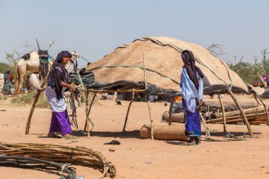 Nomad women build traditional hut in Sahara desert Niger clipart