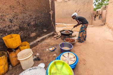 Renkli elbiseli Nijer Afrikalı kız ve türbanlı geleneksel tatlı kurabiyeler yapıyor. 