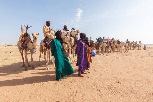 Tuareg people in traditional clothes sitting on camels in Sahara desert