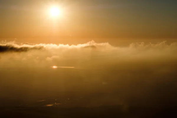 A bird's eye view of the sun over the horizon, minutes after sunrise,  with a reflection of a distant water pond, northern Israel.