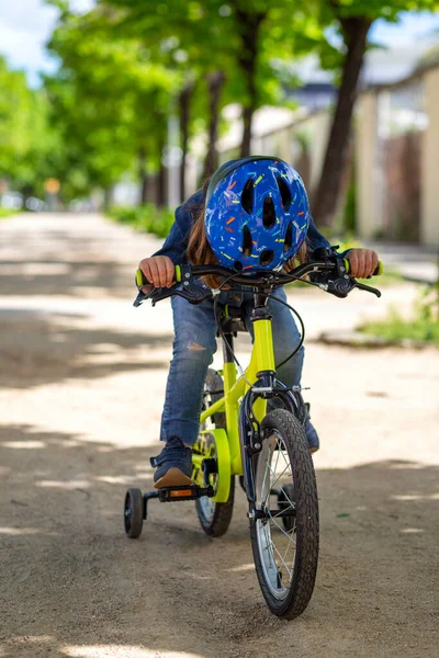 Little girl with a yellow bicycle wearing a mask and blue jacket and jeans