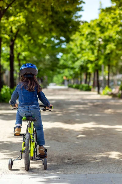 Little girl with a yellow bicycle wearing a mask and blue jacket and jeans